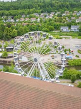 Ferris wheel in a natural environment with green landscape and city view from above, construction