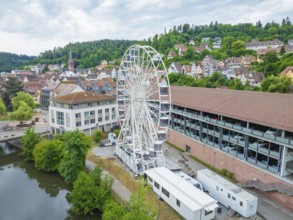 A Ferris wheel in a charming cityscape with a river and wooded hills in the background, Ferris