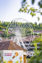 White Ferris wheel with buildings and advertising in the foreground, Ferris wheel construction for