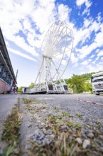 Ferris wheel under construction next to a white lorry under a blue, cloudy sky, Ferris wheel