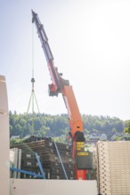 A crane lifts a heavy load in front of a cloudy sky, Ferris wheel construction for the 950th