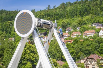 Workers on ladders building a Ferris wheel with a view of a village in the background, Ferris wheel