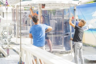 People working on a glass cabin of a Ferris wheel in an amusement park, Ferris wheel construction