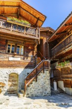 Old wooden houses in log construction, decorated with flowers, historic village centre, Grimentz,