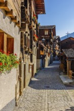 Old wooden houses decorated with flowers, in the village street, historic village centre, Grimentz,