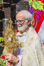 The priest with the golden monstrance during the Corpus Christi procession, historic village