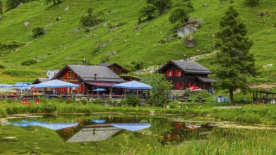 Huts and parasols reflected in the pond, Relais Tzoucdana, Zinal, Val d'Anniviers, Valais Alps,