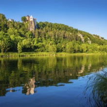 Prunn Castle on a steep cliff above the Altmühl Valley in the evening light, reflection in the