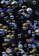 Many, small iridescent and floating soap bubbles against a black background, Recklinghausen, North
