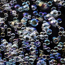 Many, small iridescent and floating soap bubbles against a black background, Recklinghausen, North