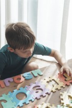 Child assembling colorful puzzle pieces on a wooden table in a bright indoor space during the day