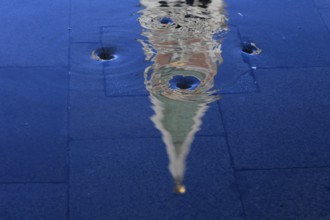 Reflection of the Campanile with water vortex of the flowing flood water, Acqua alta, Venice,