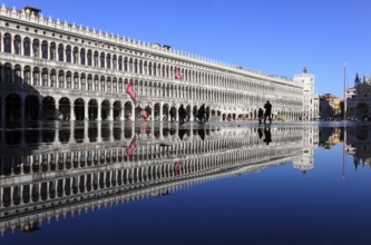 St Mark's Square, reflection of the Procuratie and the clock tower during the Acqua alta, Venice,
