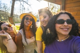Four cheerful women enjoying a sunny day in the park, smiling and capturing memories together while