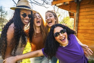 Four multi ethnic female friends are having fun together in a park, laughing and enjoying each