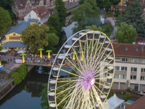 Night shot of an illuminated Ferris wheel next to a river and a bridge, 950 years of Calw, Germany