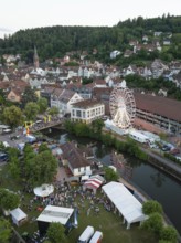 City festival with Ferris wheel and tents by the river on wooded hills, 950 years of Calw, Germany