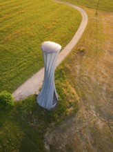 Modern tower on a field with a curved path in the evening light