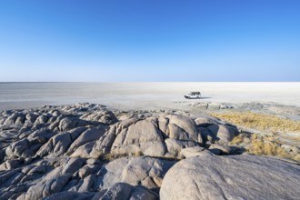 Round rocks of Kubu Island with view over the salt pan, off-road vehicle on the salt pan, Kubu