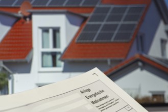 Close-up of tax return, energy measures attachment, in the background a picture of a solar roof on