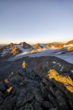 Mountaineers in front of a picturesque high mountain landscape at sunrise with alpenglow, glacier