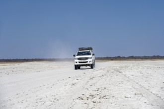 Off-road vehicle driving on a wide empty salt pan, Makgadikgadi Salt Pans, Botswana