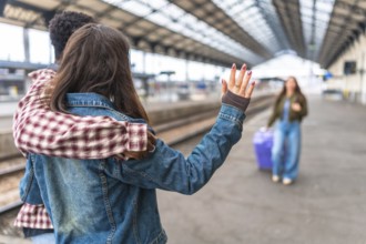 Couple waving goodbye to their friend at the train station, sharing a heartfelt moment filled with