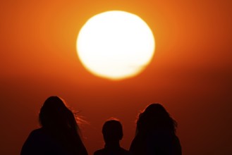 People watching the sun set on the horizon from the summit of the Großer Feldberg in the Taunus,