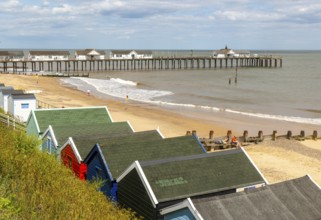 View over beach huts to sandy beach and pier, Southwold, Suffolk, England, UK