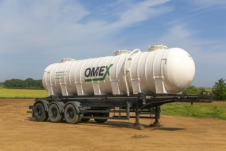 Omex fertiliser road tanker container waggon standing in field, Alderton, Suffolk, England, UK