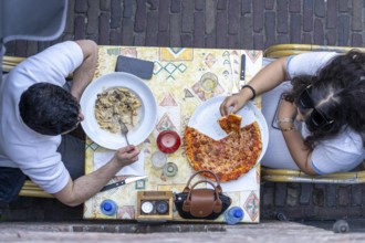 Man and woman sitting in an Italian restaurant eating pizza and pasta, symbolic picture