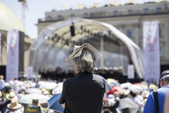 A visitor protects himself from the sun with a newspaper on his head at the Staatsoper für alle, a