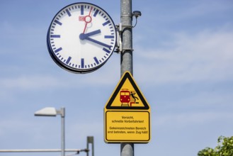 Platform with signs, station clock and warning sign Caution, fast passing. Karlsruhe,
