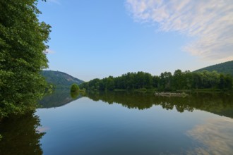 A clear blue sky with scattered clouds reflected on a quiet river, summer, Grünenwört, Wertheim,