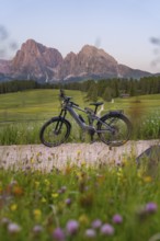 E-bike on a gravel road in front of the imposing silhouette of the Dolomites in the evening light,