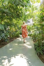Woman in a red dress walks amidst lush vegetation in the botanical garden, Botanical Garden, The
