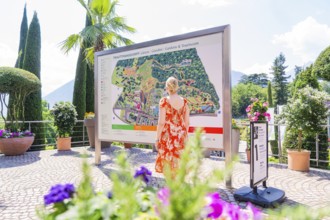 Woman in front of an information board in a sunny garden area, Botanical Garden, The Gardens of