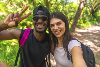 Smiling hikers capturing a selfie while enjoying their adventure on a bright, sunny day in the lush