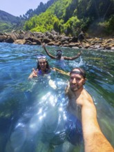 Three friends enjoy snorkeling in the refreshing ocean water, capturing a selfie moment amidst a