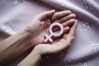 Woman's hands cradling glossy female gender symbol. A visual tribute to strength, femininity, and