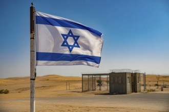 Israeli flag waving in desert wind near military checkpoint under harsh sunlight. Generative ai, AI