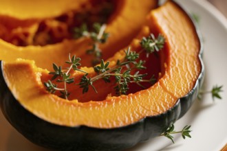 Caramelized roasted pumpkin slices with thyme. A close-up view of seasonal comfort food in warm,