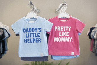 Pink and blue children's shirts with stereotypical text, highlighting early gender norms and