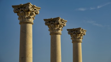 Three ornate ancient columns rising against the blue sky, Temple of Apollo, Corinthian Columns,