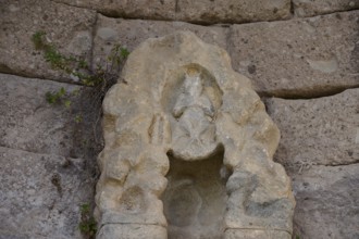 Stone sculpture in ancient wall with natural vegetation, arcade, lower terrace, Pan, Asklipion,