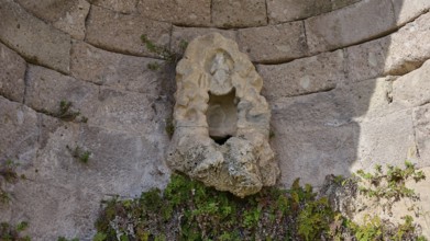Sculpture in an ancient round arch, surrounded by plants and masonry, arcade, lower terrace, Pan,