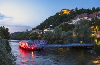 Night-time view of the Murinsel floating island on the river Mur with Schlossberg castle hill in