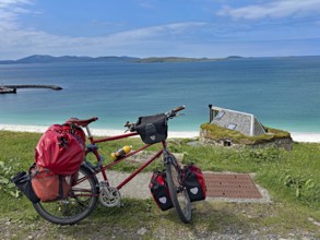 Luggage-laden bicycle in front of turquoise sea and blue sky on a rocky coastal landscape, cycle