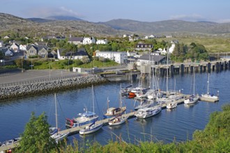 Small harbour with sailing boats in front of a coastal town in a hilly landscape, Tarbert, Isle of