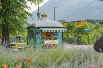 Small kiosk in a scenic park setting with mountains and flowers, Merano, Italy